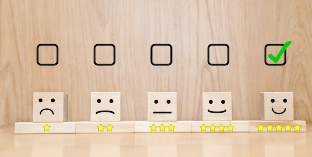 사진 고객 서비스 평가 및 만족도 조사 개념. 선택한 확인란 행복한 얼굴 미소와 테이블 위의 나무 큐브에 5개의 별 기호