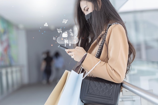 Photo customer service evaluation concept smiling asian woman is using a smartphone and she is pressing face emoticon smile in satisfaction on virtual touch screen