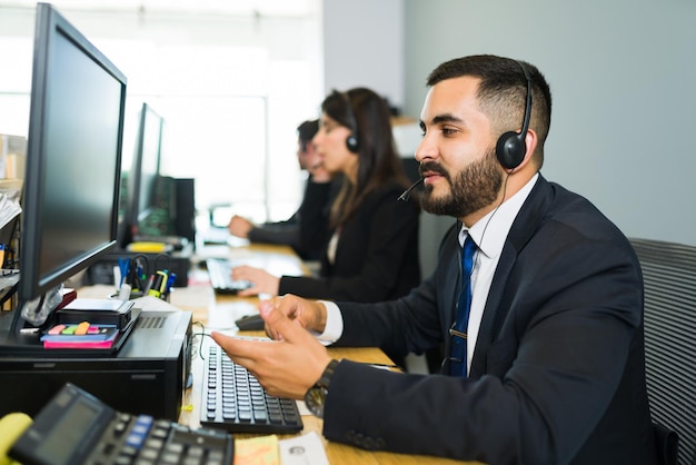 Customer service executive receiving a call from a client and offering tech support. Handsome sales representative working at a call center