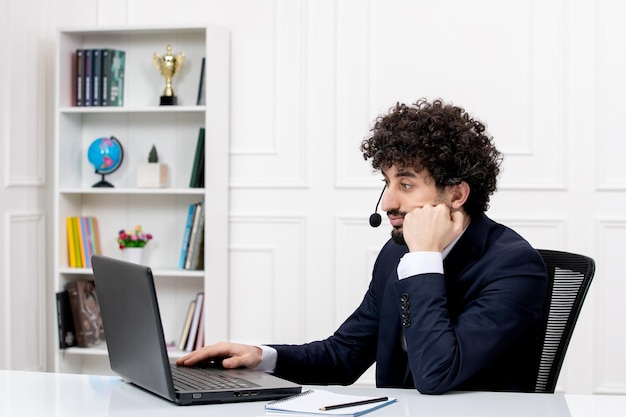 Customer service handsome curly man in office suit with computer and headset working