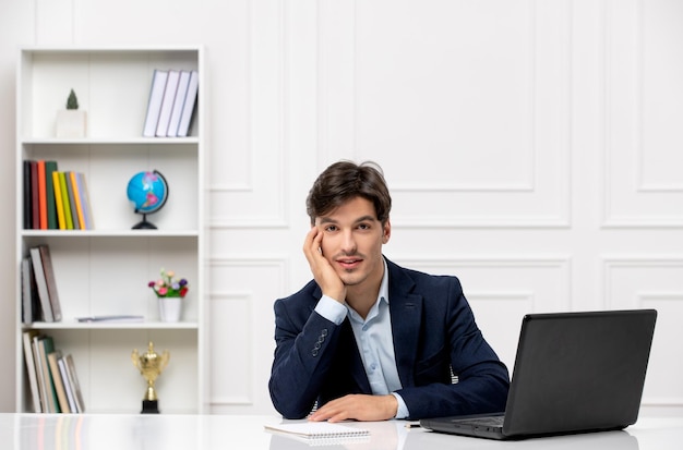 Customer service handsome guy in the office suit with the computer thinking with the shelf behind