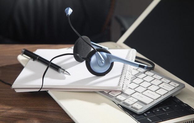 Photo customer service headset computer keyboard and business objects on the wooden table