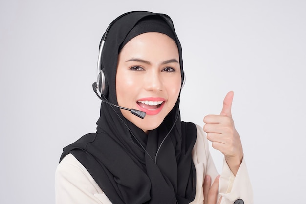흰색 배경 스튜디오 위에 헤드셋을 착용한 정장을 입은 고객 서비스 운영자 이슬람 여성