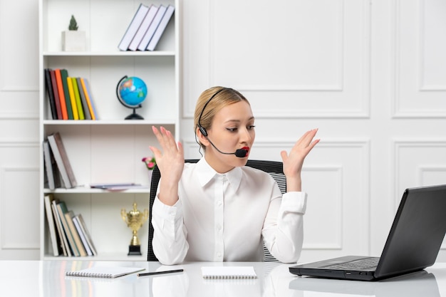 Customer service pretty blonde girl in white shirt with laptop and headset confused waving hands