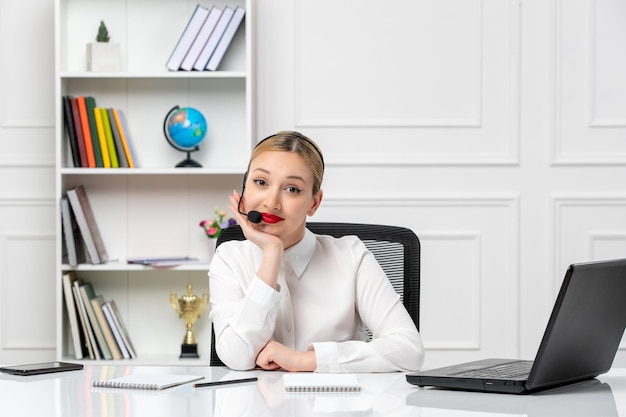 Photo customer service pretty blonde girl in white shirt with laptop and headset smiling in a cute way