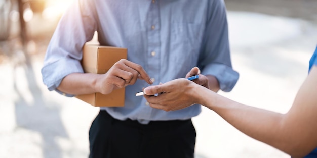 Customer signature in mobile phone man receiving parcel box from courier with delivery service man express delivery online shopping concept