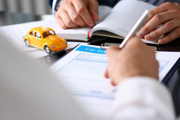 Клиент подписывает документ о страховании автомобиля или бумажный договор аренды или договор