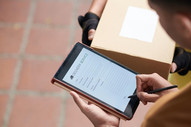 Customer signing delivery service document on tablet computer after receiving package