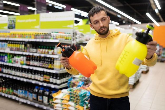 A customer in a store for gardening goods chooses a garden sprayer