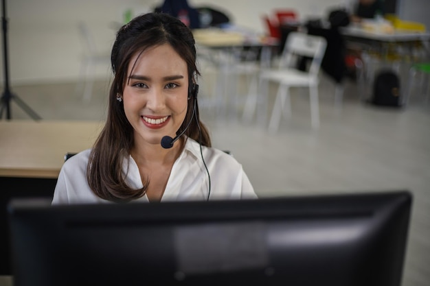 Photo customer support agent with headset works on desktop computer call center supporting the customer