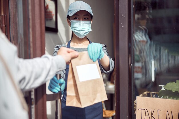 Customer taking package with food from cashier at cafe