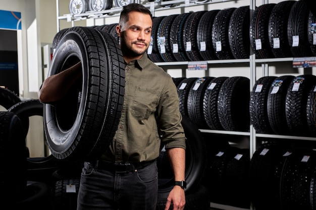 Montaggio pneumatici del cliente nel servizio auto, meccanico auto controlla il pneumatico e il battistrada in gomma per la sicurezza, concetto: riparazione di macchine, diagnosi guasti, riparazione. uomo acquista nel negozio di servizi di auto