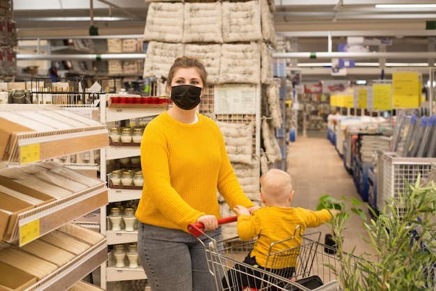 Foto un cliente con un bambino in mascherina usa e getta sceglie gli articoli di arredamento per la casa nel negozio la nuova normalità