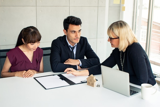 Customers consult with the owner on the contract of house sale.  Couples make purchasing a home with a company that can make a home. Husband and wife were signed to purchase a home.