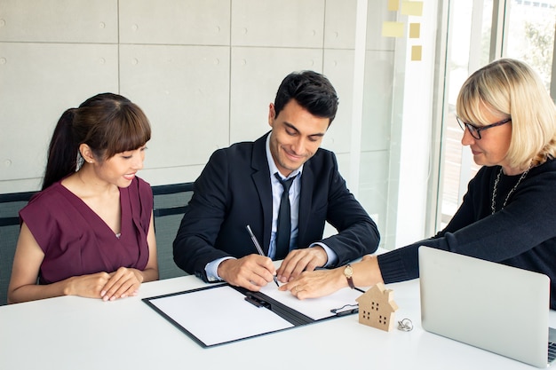 Customers consult with the owner on the contract of house sale.  Couples make purchasing a home with a company that can make a home. Husband and wife were signed to purchase a home.