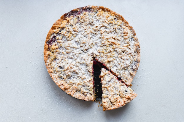 Cut berry pie. slice of homemade sour cherry pie on plate and whole tart cut in slices in baking dish on napkin on wooden table, classic recipe, view from above