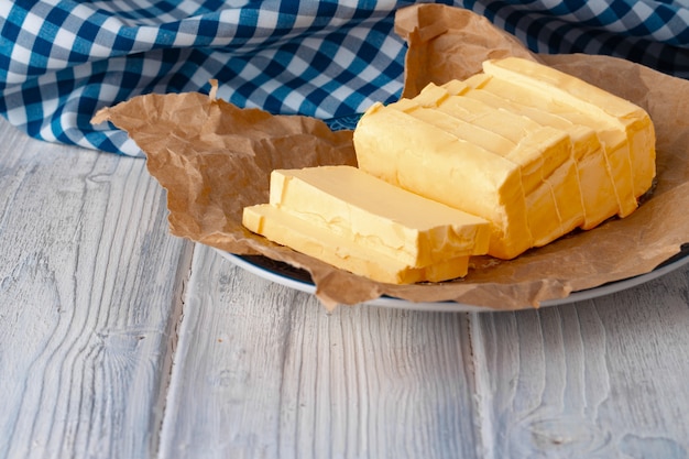 Cut butter on plate with blue towel on kitchen table