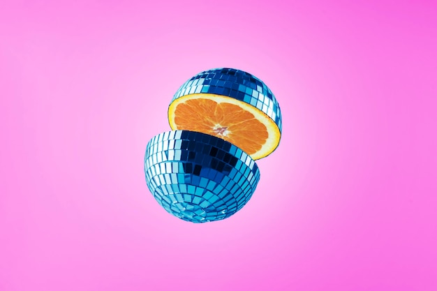 Foto tagliare la palla da discoteca con l'interno arancione su sfondo viola collage di frutta creativa