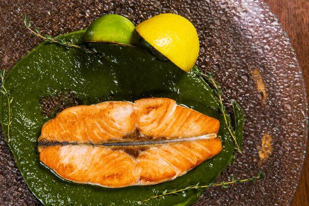 Cut fish with lemon and sauce in glass plate on wooden table in luxury restaurant