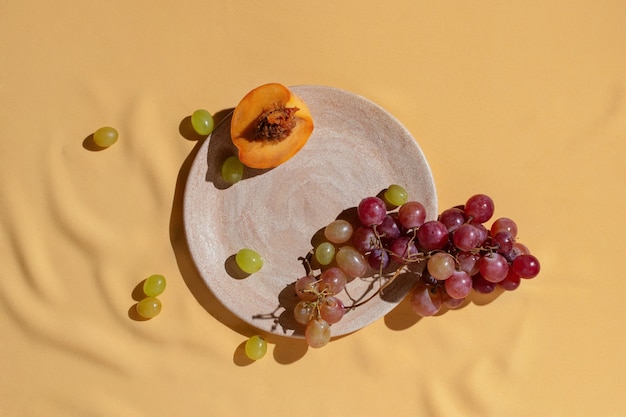 Photo cut fresh peach and grape on homemade ceramic plate on yellow tablecloth