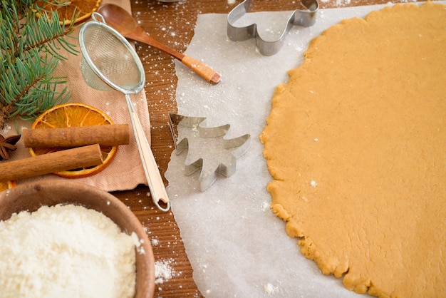 Cut gingerbread out of the dough using a gingerbread mold, top view, rolling pin, cinnamon and dried orange next.