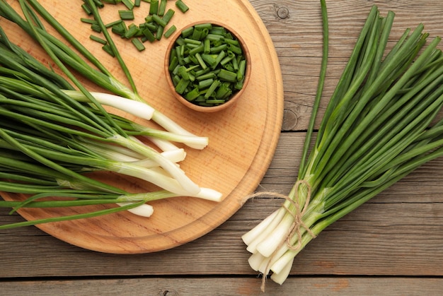 Tagliare la cipolla verde su fondo di legno grigio