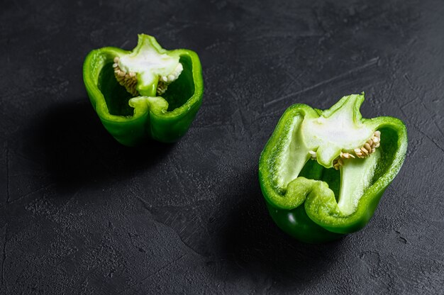 Photo cut green sweet pepper, two halves. black background. top view.