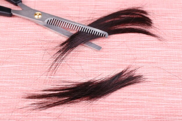 Cut hair and scissors on tile background