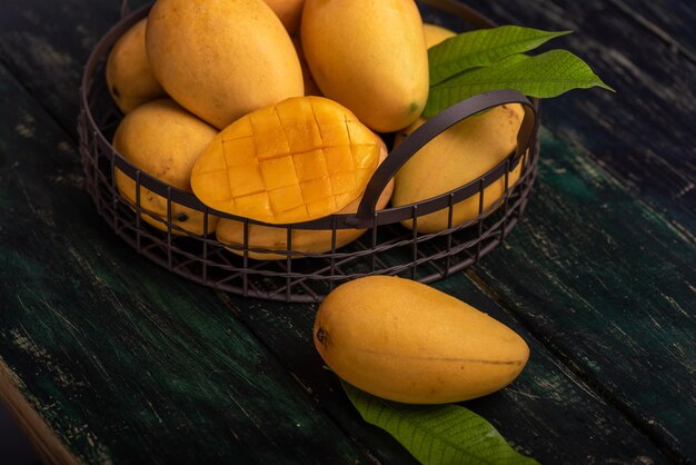 Cut and intact mangoes in the dark background