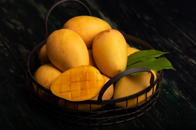 Photo cut and intact mangoes in the dark background