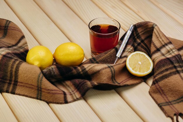 Photo cut lemon with warm tea thermometer scarf wooden board autumn on dark background