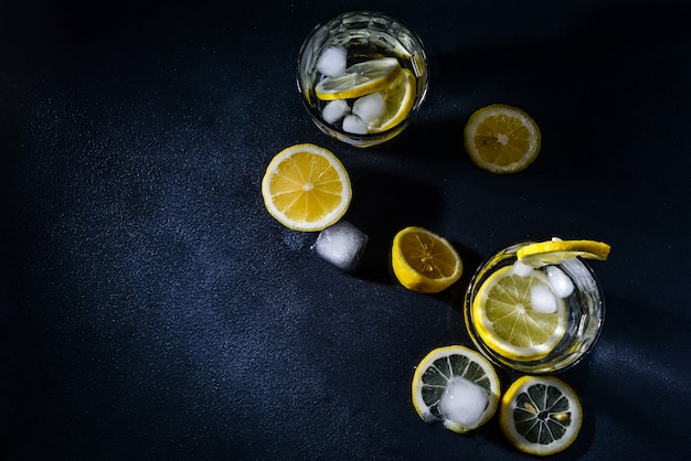 Tagliare i limoni con fettine di limone e cubetti di ghiaccio su sfondo scuro. vista dall'alto. avvicinamento