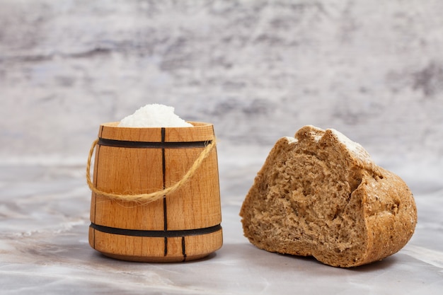 Tagliare la pagnotta di pane di segale con una saliera in legno sul tavolo della cucina