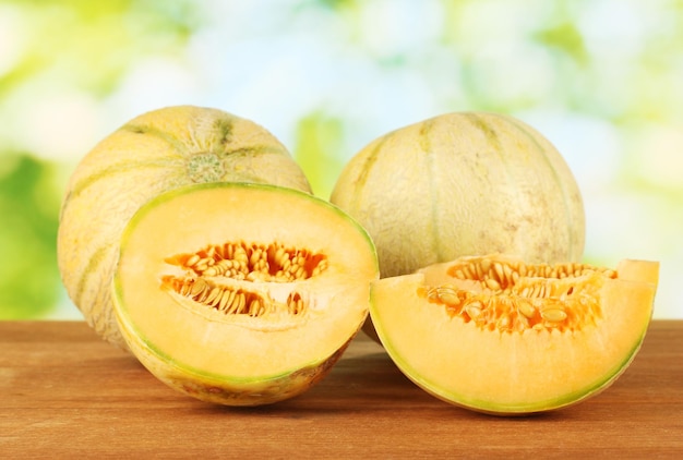 Cut melon on wooden table on green background