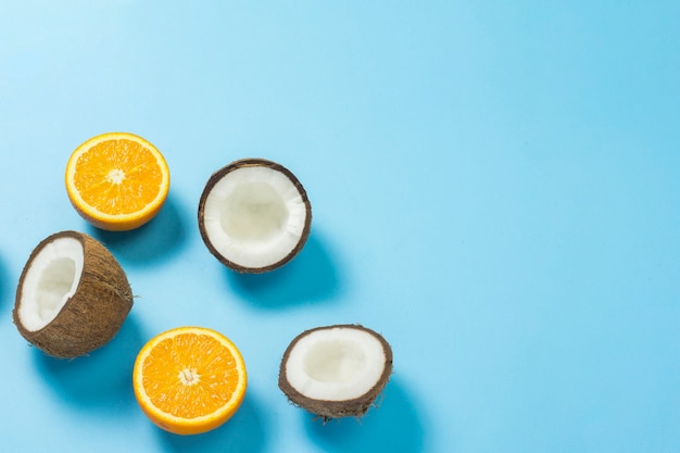 Cut orange and coconut on a blue surface. 