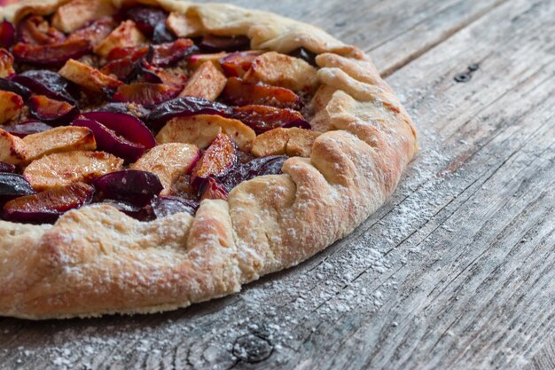 Cut out of a fresh plum cake on a rustic wooden table summer