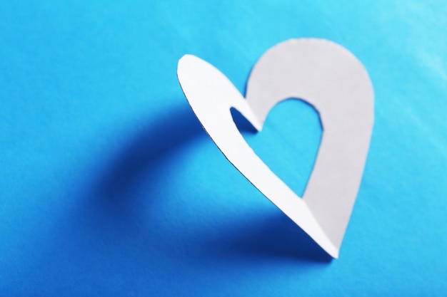 Вырежьте сердце из белой бумаги на синем фоне