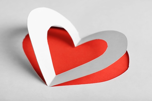 Cut out white paper heart on red background