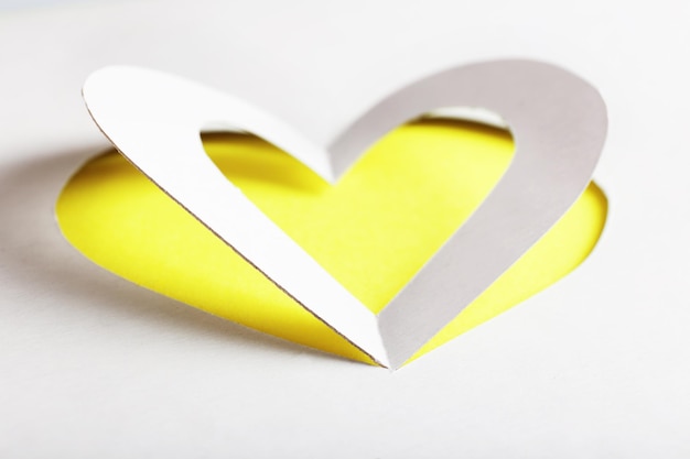 Cut out white paper heart on yellow background