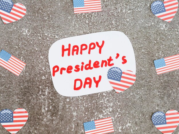 Cut paper american flags with congratulations on the sheet happy president day lie on a gray stone top view close-up