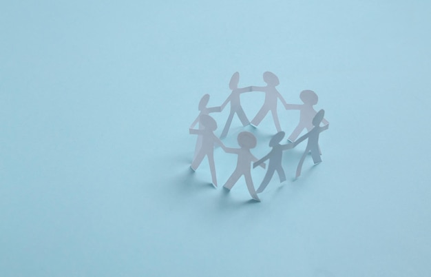 Cut paper human chain hold hands and show their unity on blue\
background solidarity and peace