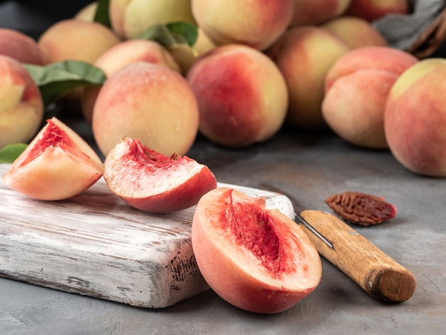 The cut peach lies on the table and on a cutting board with a knife.