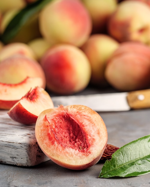 The cut peach lies on the table and on a cutting board with a knife.