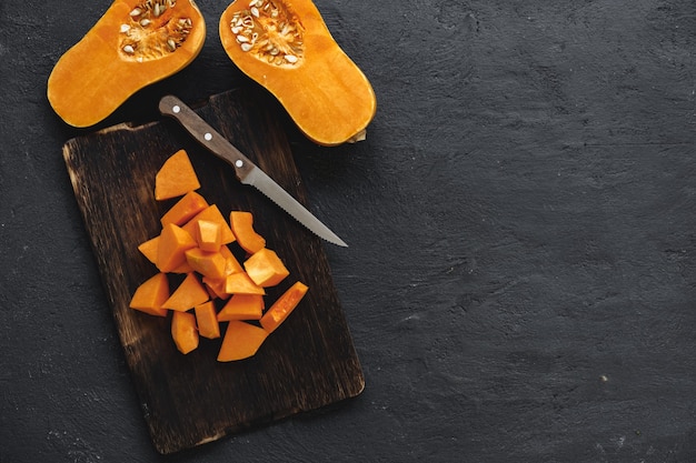 Cut pieces of raw pumpkin on wooden cutting board on table