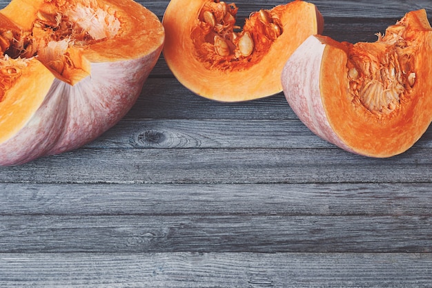 Photo cut pumpkin slices on gray wooden table with copy space