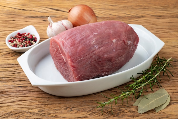 Cut raw eye round meat over white plate with seasonings.