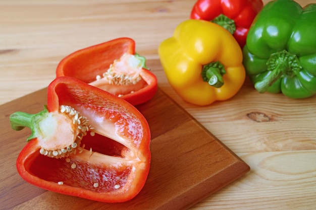 Cut red bell pepper on cutting board with tricolor bell peppers