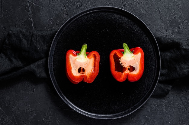 Cut red sweet pepper, two halves. Black background. Top view. Space for text