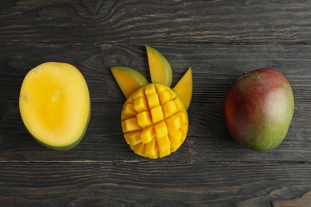 Cut ripe mangoes on wooden table, top view