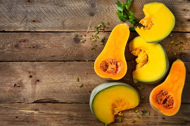 素朴な木の種子とハーブの熟したオレンジ色のカボチャをカットします。ベジタリアンや生の有機健康食品のコンセプト、ダイエット。
